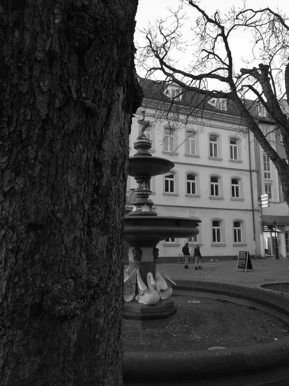 grayscale photography of fountain beside building