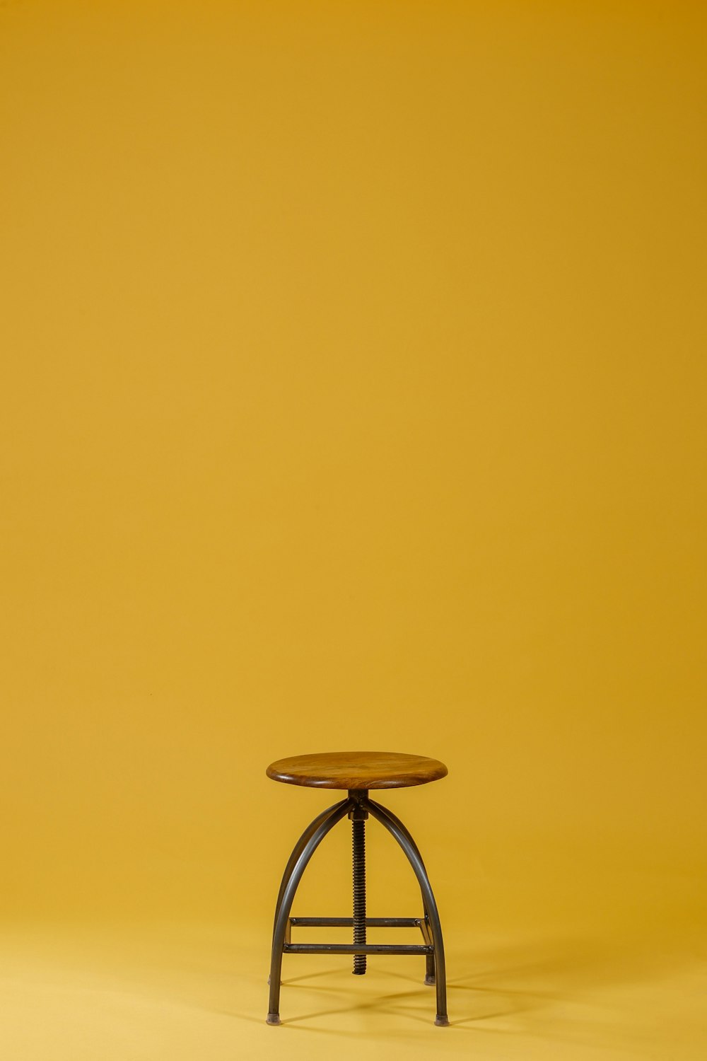 runde braune Holzplatte und schwarzer Stuhl auf gelbem Hintergrund