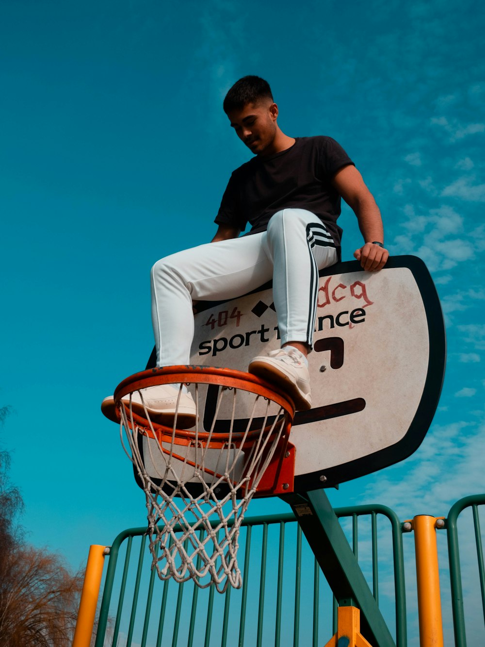 man sitting on basketball hoop