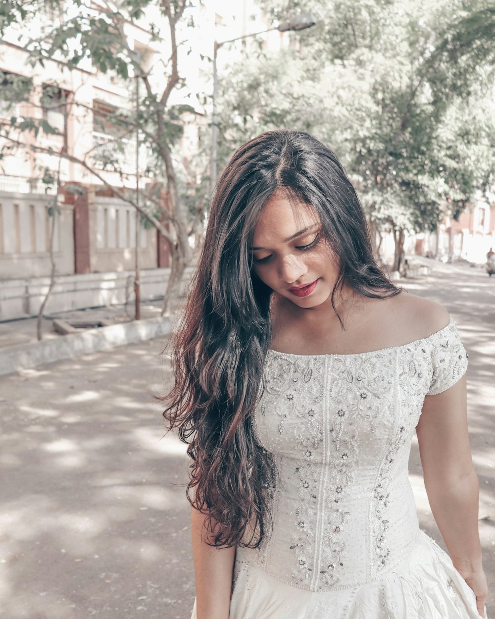 woman wearing white floral strapless dress across green trees