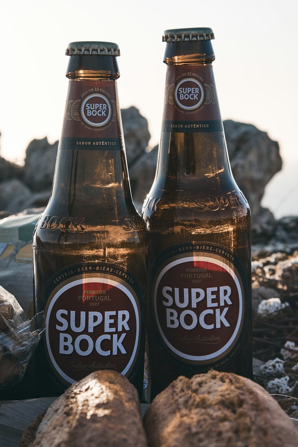 two Super Bock bottles near stones