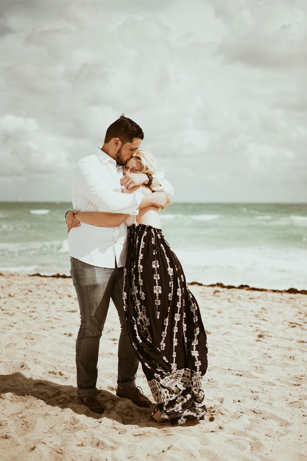 couple hugging near seashore during daytime