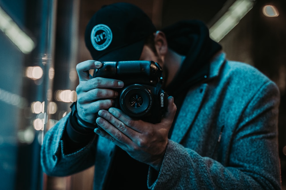 man in black cap holding camera