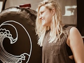 A cheerful blonde woman demonstrating towing techniques beside a tow truck.
