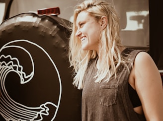 A smiling blonde woman demonstrating towing procedures beside a truck.