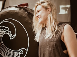 A cheerful blonde woman demonstrating towing techniques beside a tow truck.
