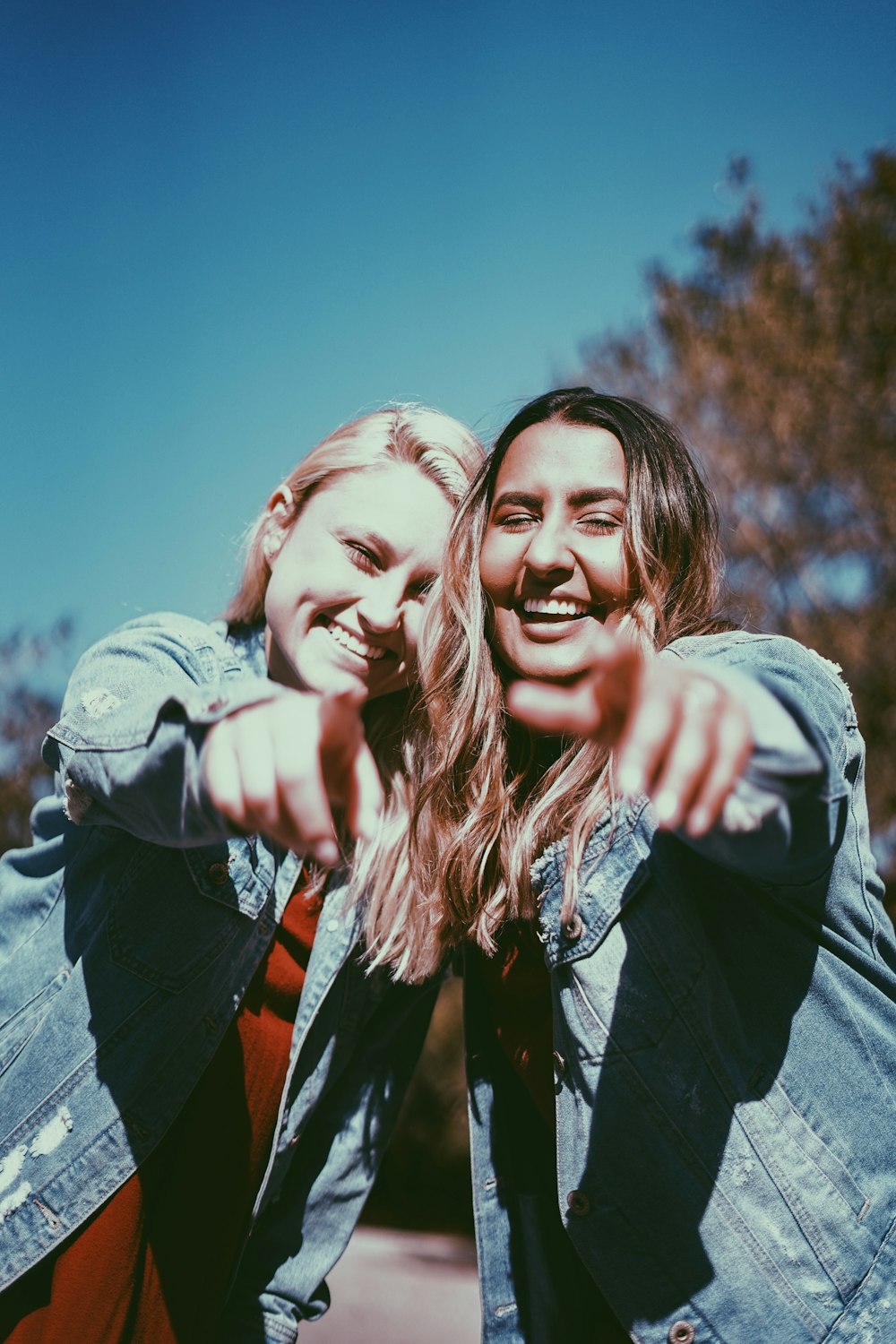 two women smiling while pointing fingers