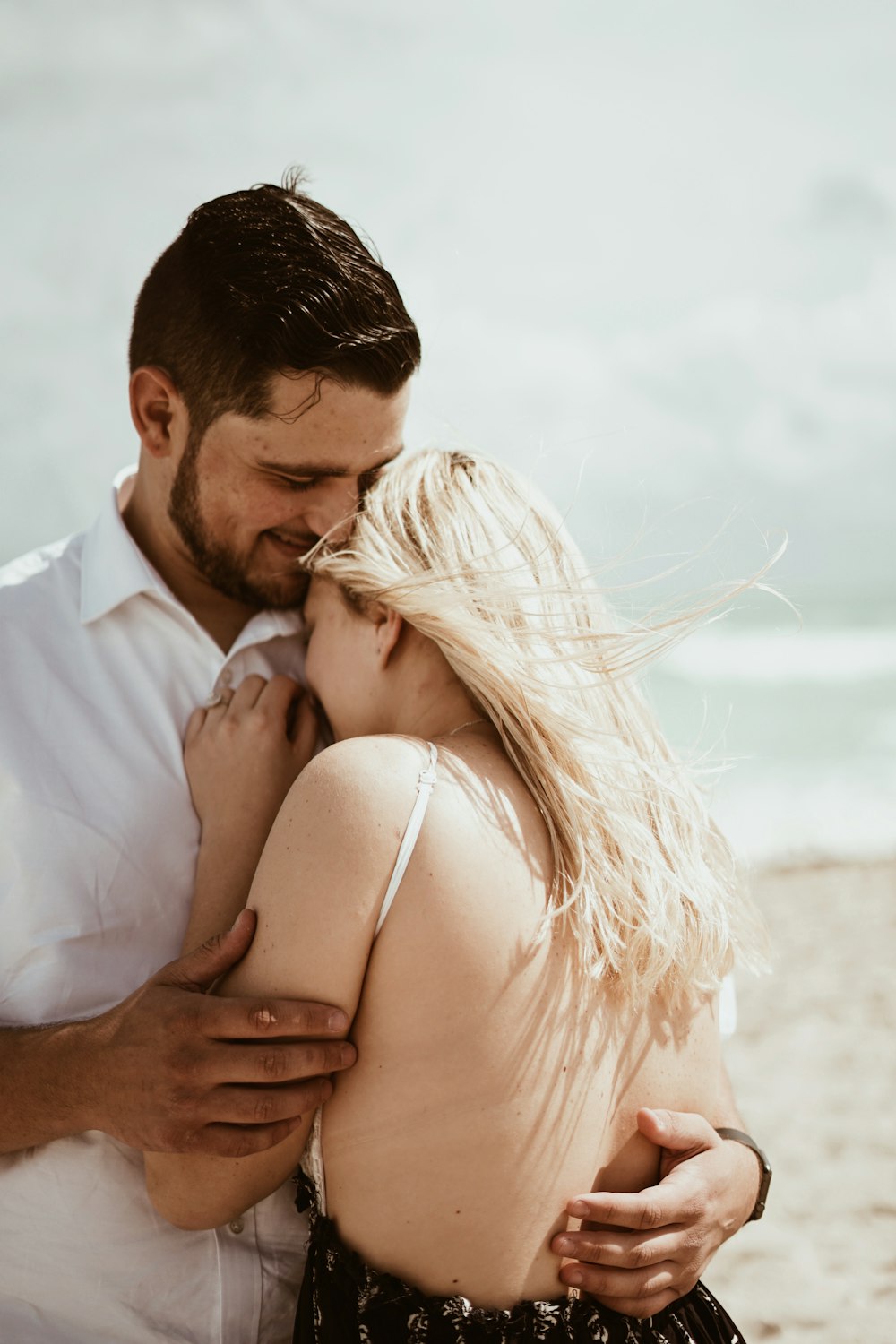 pareja abrazándose cerca de la playa durante el día