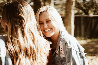A warm, candid portrait of a woman laughing outdoors at golden hour.
