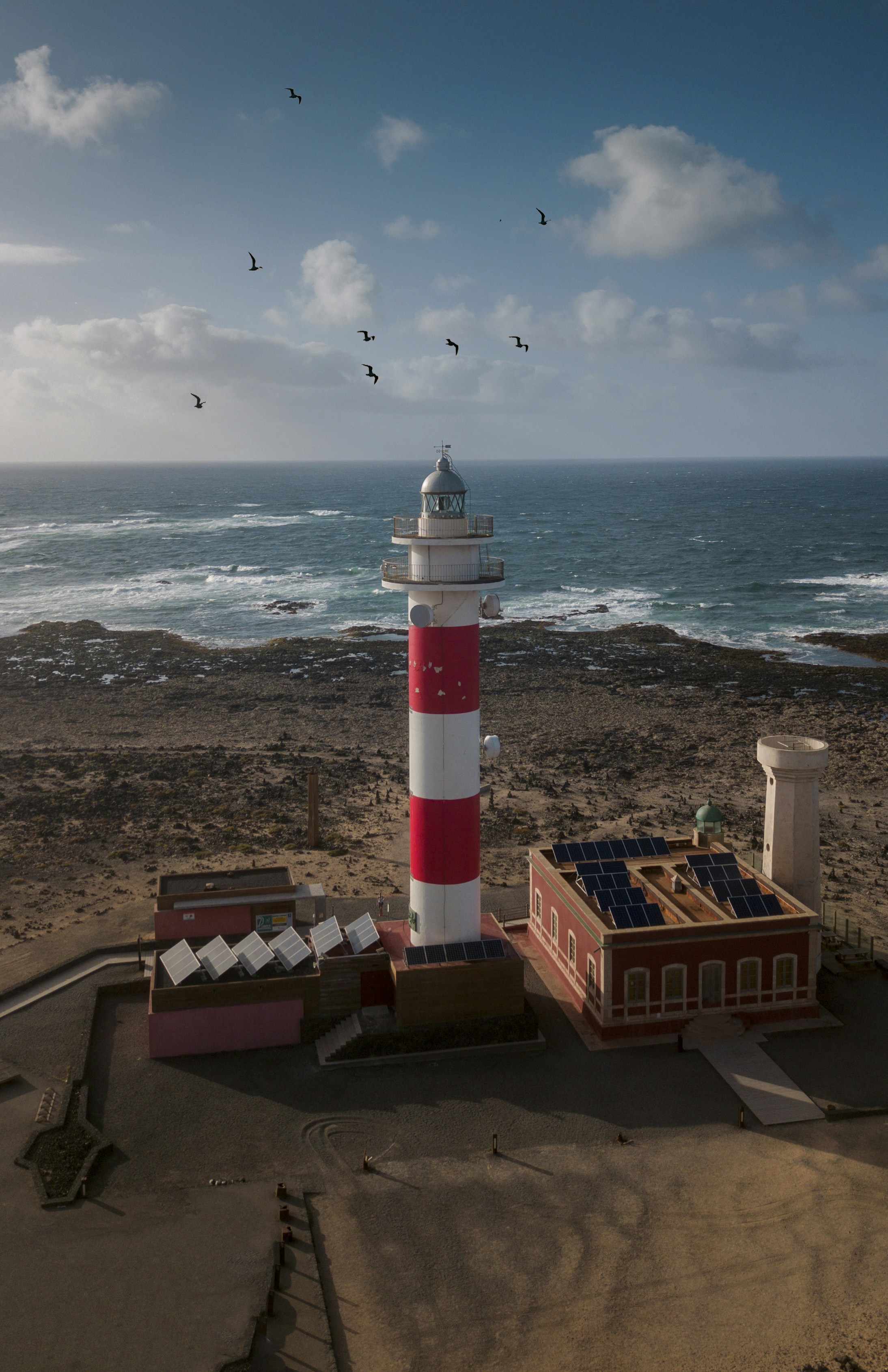 farol branco e vermelho perto do oceano durante o dia