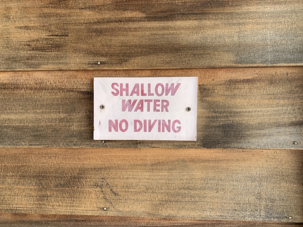 Shallow water no diving signage on wooden panel