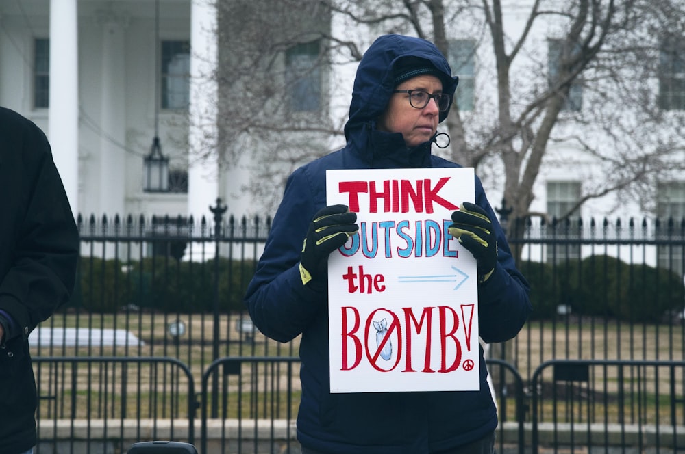 Hombre sosteniendo Piensa fuera de la señalización de la bomba durante el día