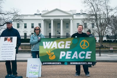 people holding wage peace signage in front of white concrete building during daytime white house teams background