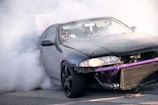A petrol muscle car spinning tires, creating thick smoke on a blacktop.