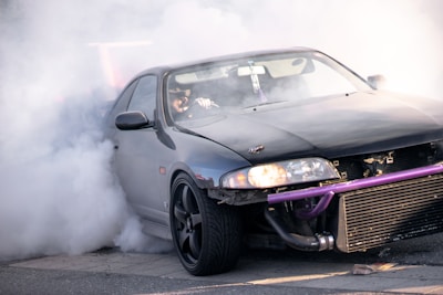 A powerful car doing a burnout with thick smoke swirling around.