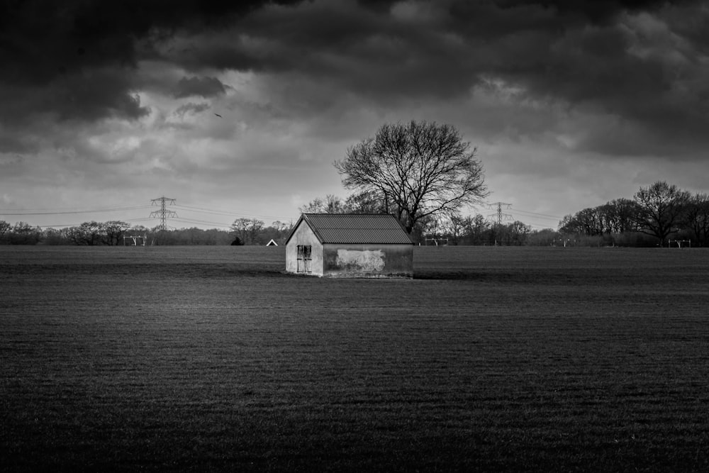 house in middle of open field greyscale photo
