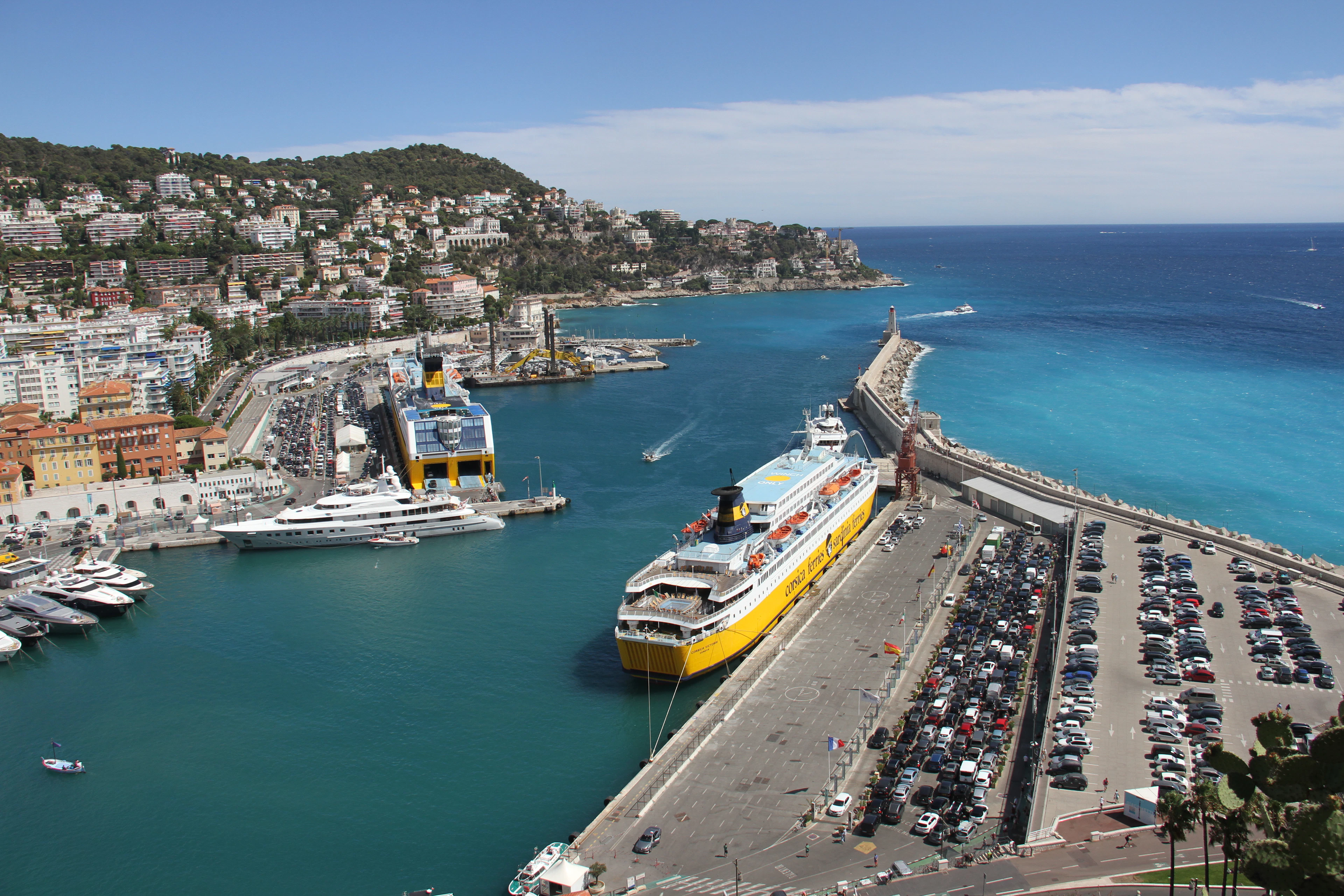 Aerial view of Nice's Port Lympia with a yellow cruise ship docked beside pastel harbor buildings and turquoise water.