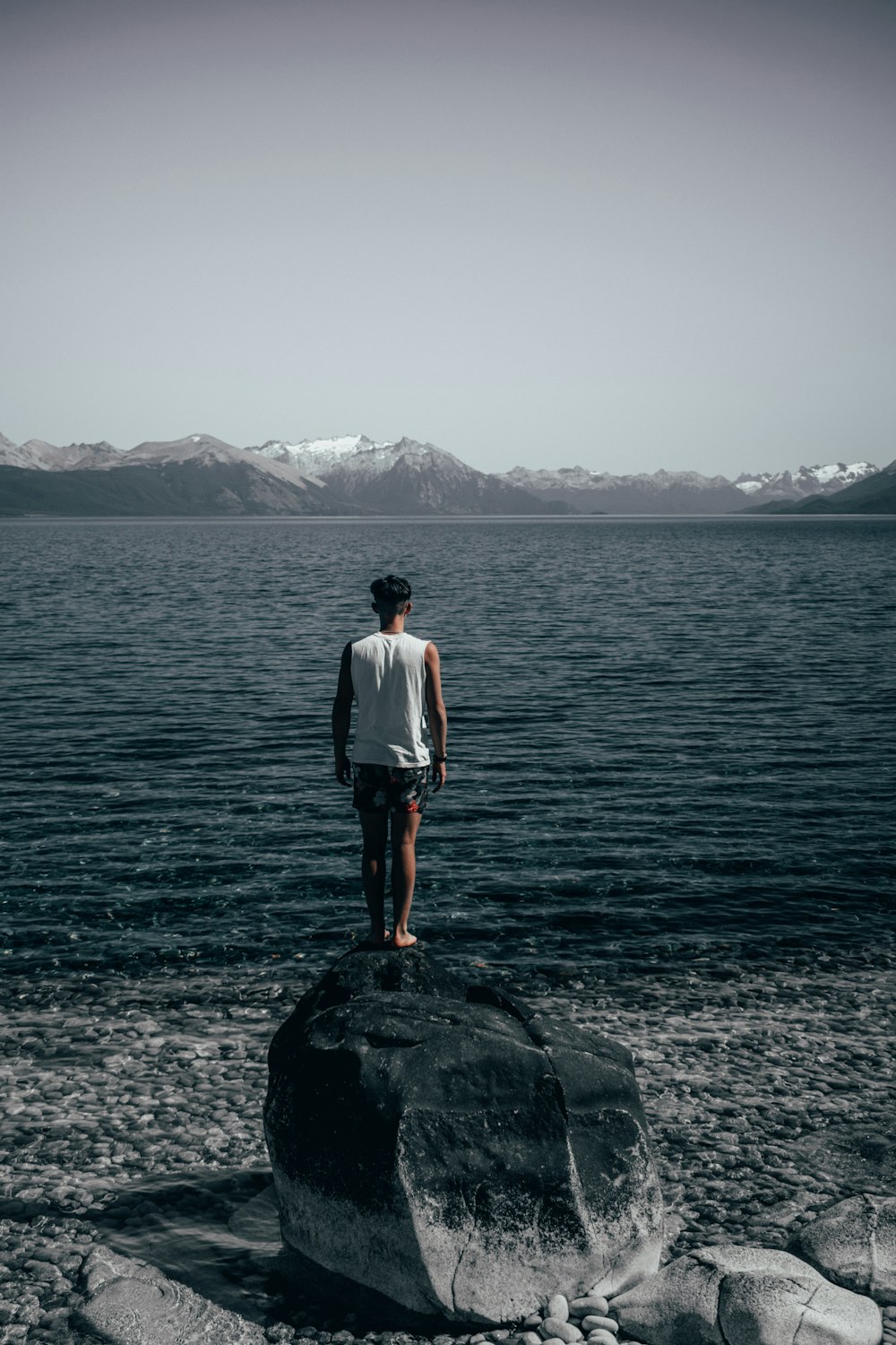 man standing on rocks looking at rippling water