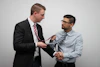 A professional handshake between two businesspeople in a modern office setting.