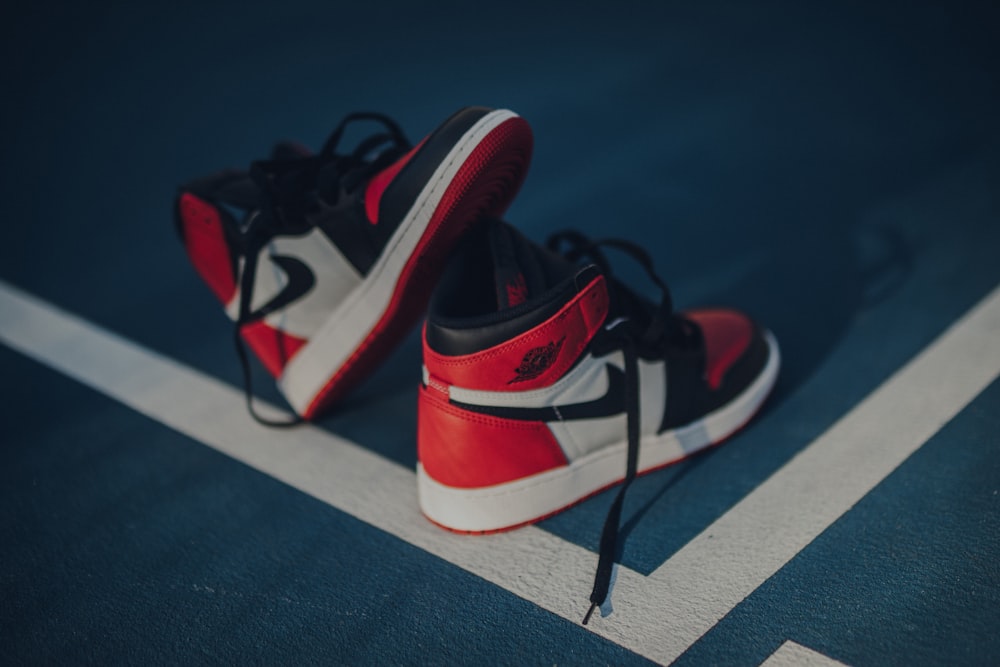pair of white-red-and-black Nike Air Jordan 1 shoes on floor