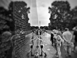 selective focus and grayscale photography of girl leaning on wall