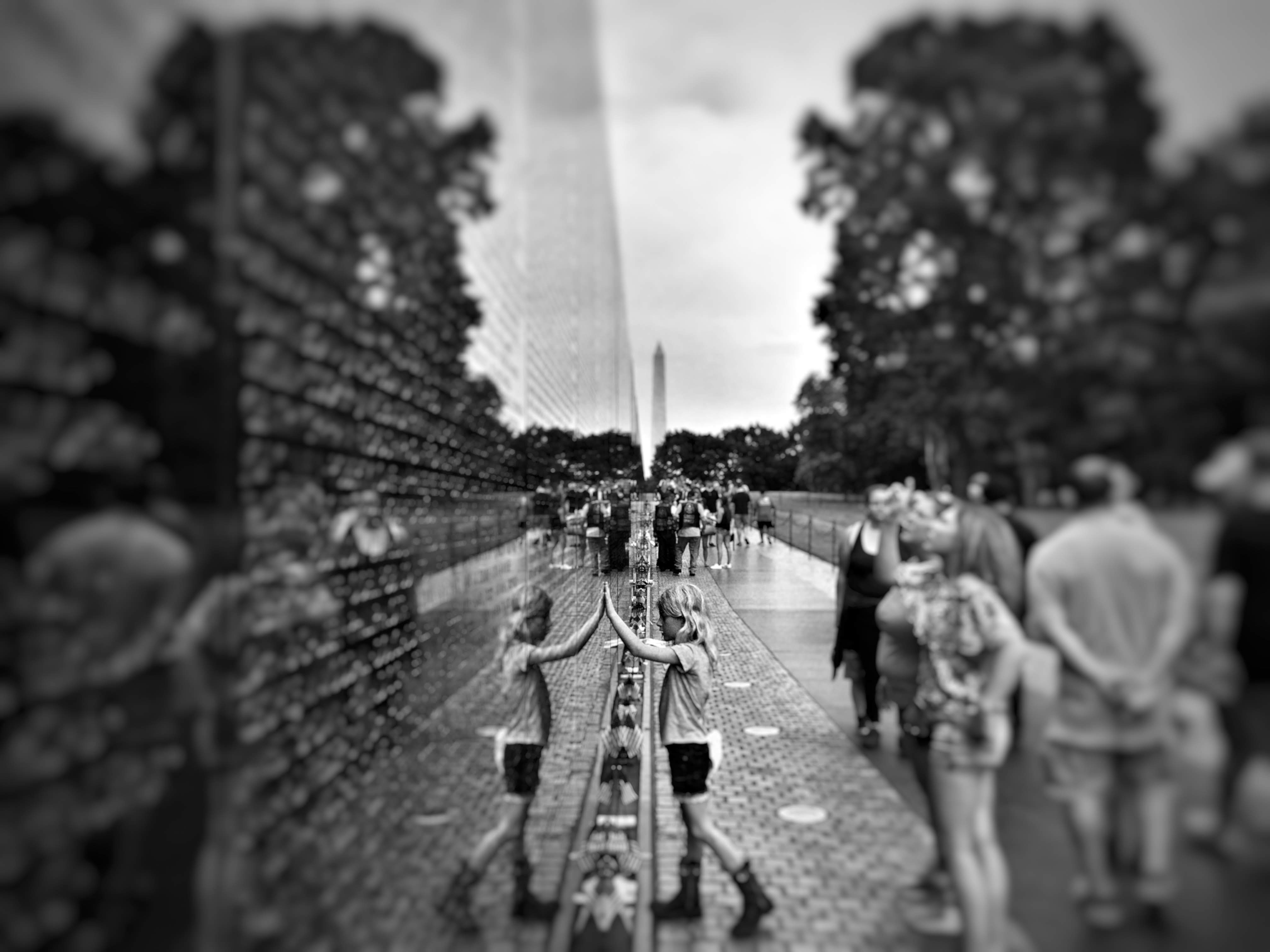 selective focus and grayscale photography of girl leaning on wall