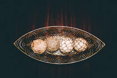 Close-up of a wooden decorative tray with brass accents and leather handles on a rustic table