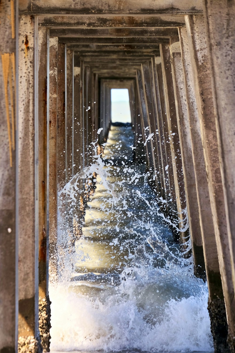 waves under brown wooden bridge