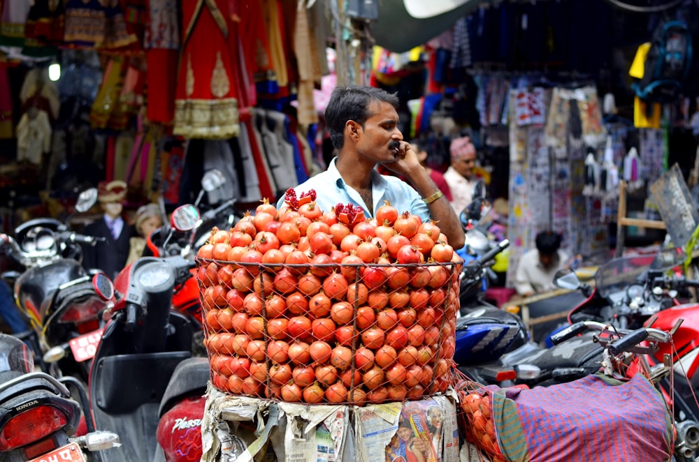 person standing in front fruit in basket while calling phone