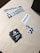 A collection of Unsplash stickers are arranged on a light wooden surface. The stickers include the Unsplash logo in various forms: two black square stickers with the logo, several white rectangular ones, and smaller square stickers with only the logo. The stickers are casually placed, creating an informal and creative mood.