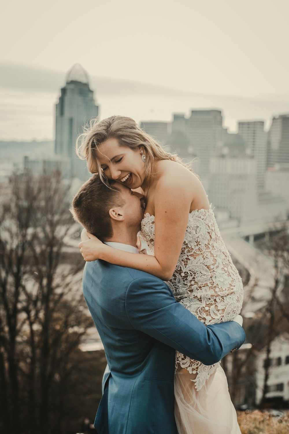 a bride and groom hugging in front of a city skyline