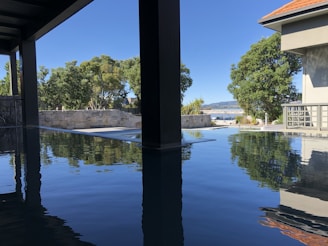 Private infinity pool reflecting the calm sea and surrounded by natural stone and wood elements.