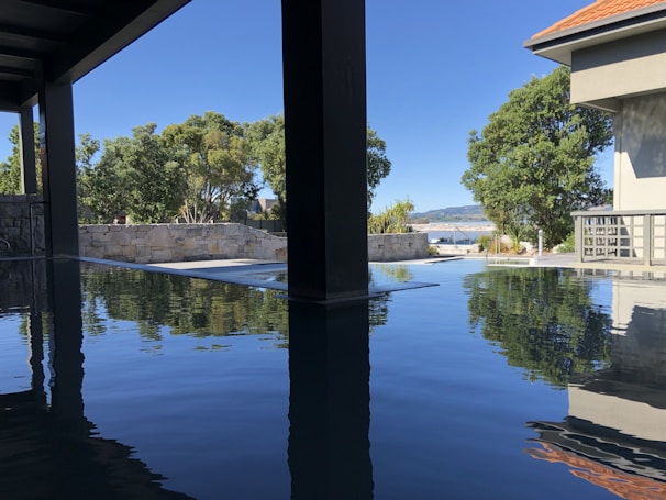 Private infinity pool reflecting the calm sea and surrounded by natural stone and wood elements.