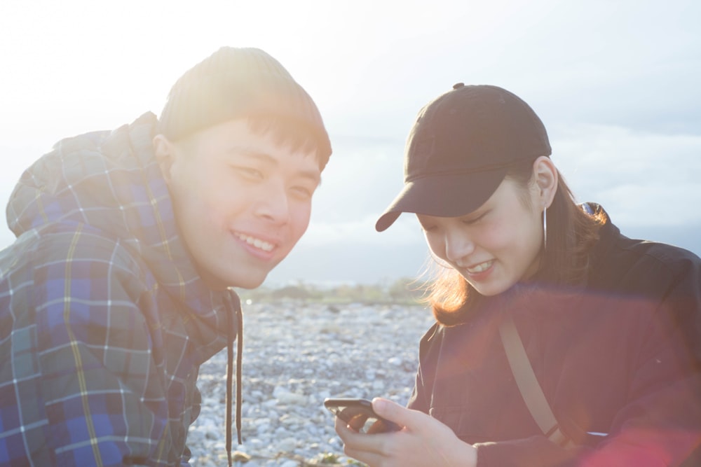 man sitting beside woman using smartphone