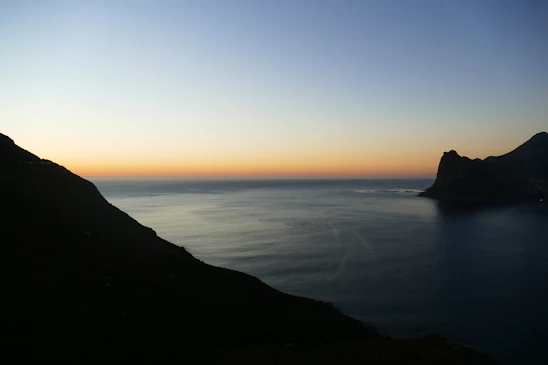 A serene Mediterranean coastal view at dusk with elegant dark tones blending into the horizon.