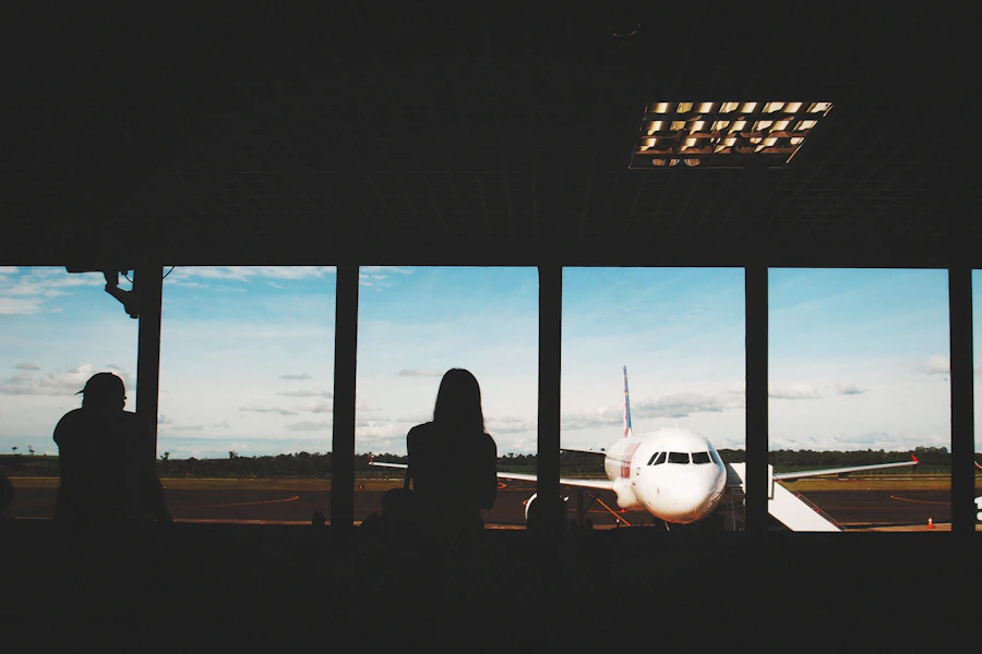 Silhouetted traveller watching aircraft move across a dark terminal window