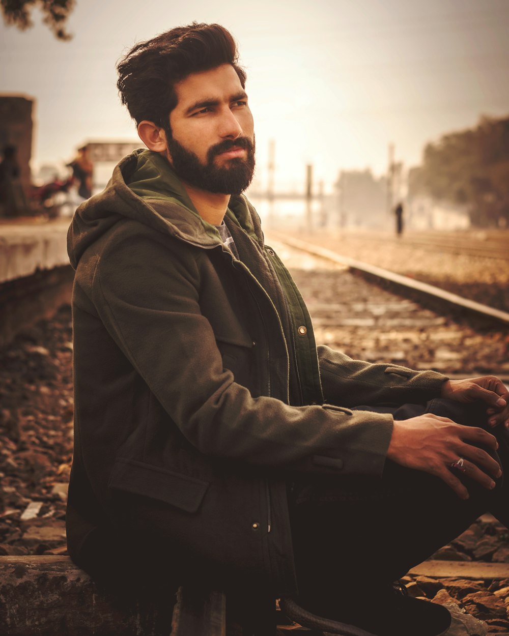 검은 재킷을 입은 남자가 철도에 앉아 있다