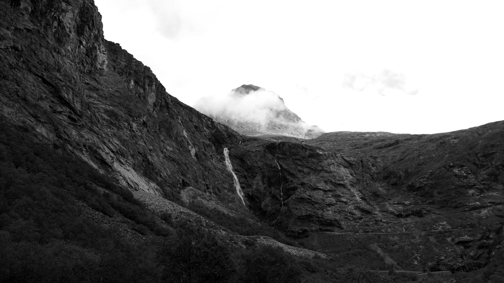 grayscale photography of smoke coming out of mountain