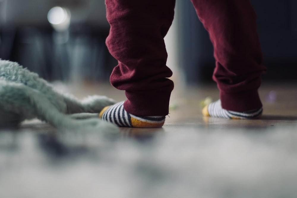 toddler's wearing socks standing next to doll on floor