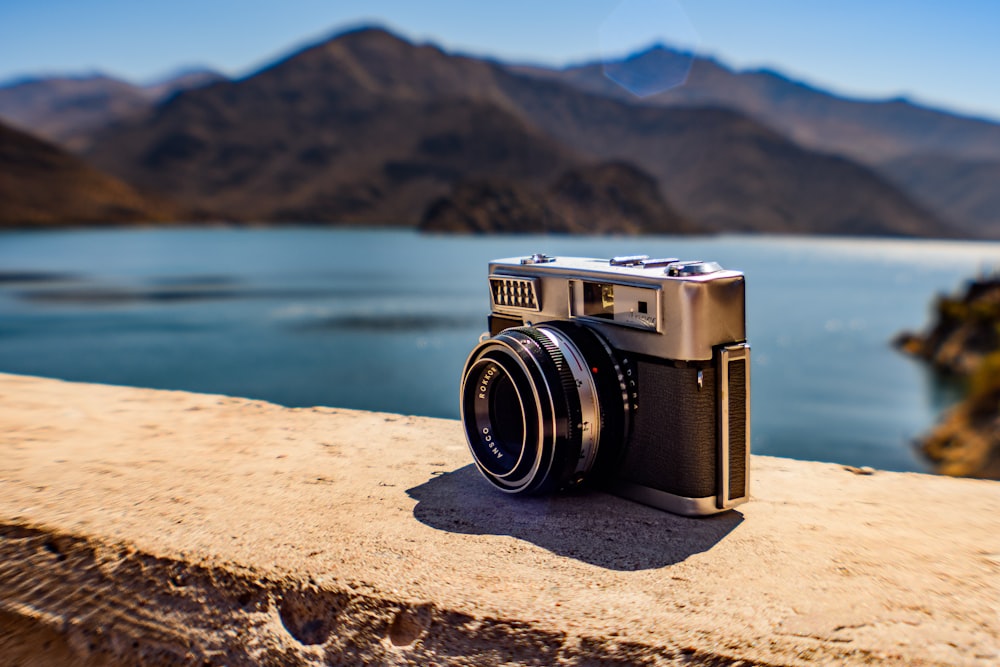 camera on rock with sea and hill behind at daytime