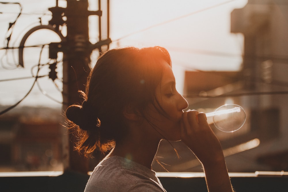 woman in grey top blowing bubbles during daytime