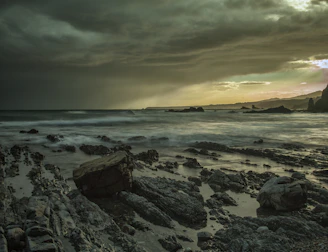 A dramatic storm rolling over the west coast, dark clouds meeting the restless sea in a dance of light and shadow.