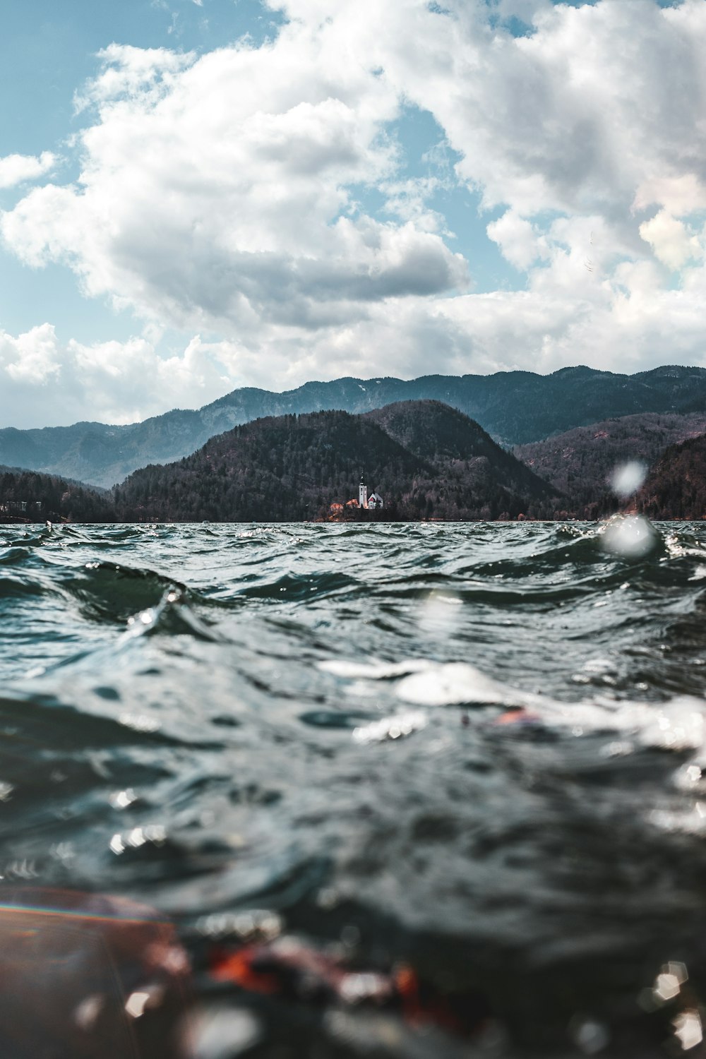 boat on water near hill under cloudy sky during daytime