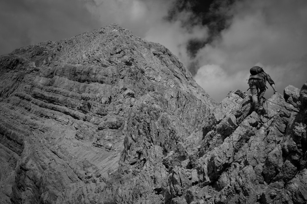grayscale photography of person climbing rock formation
