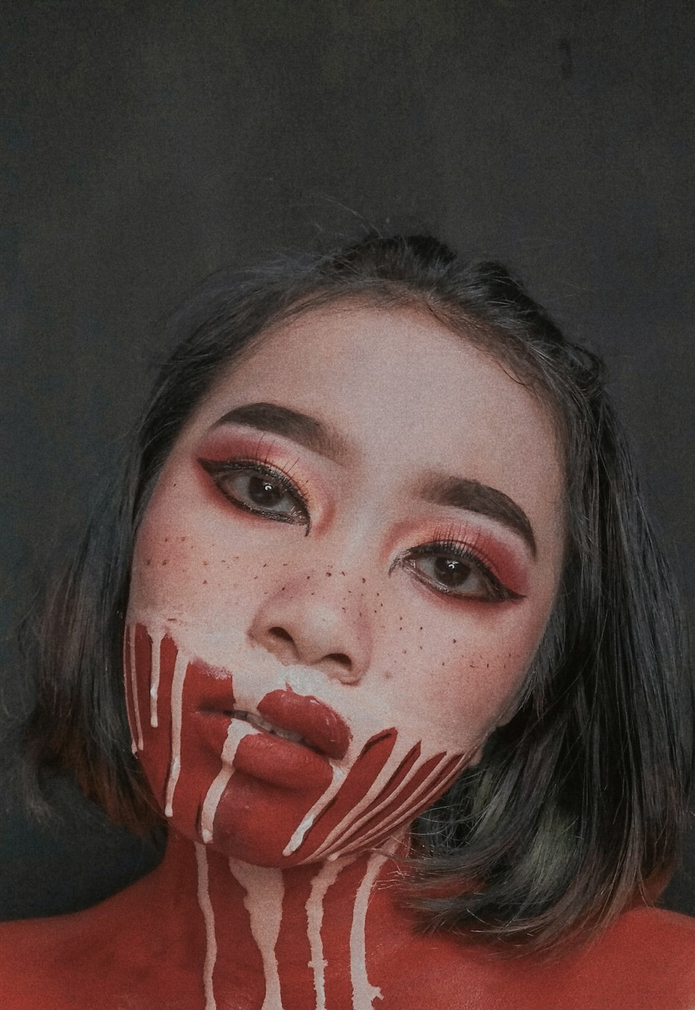 woman with red face paint taking selfie