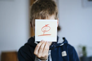 boy holds white card with drawing