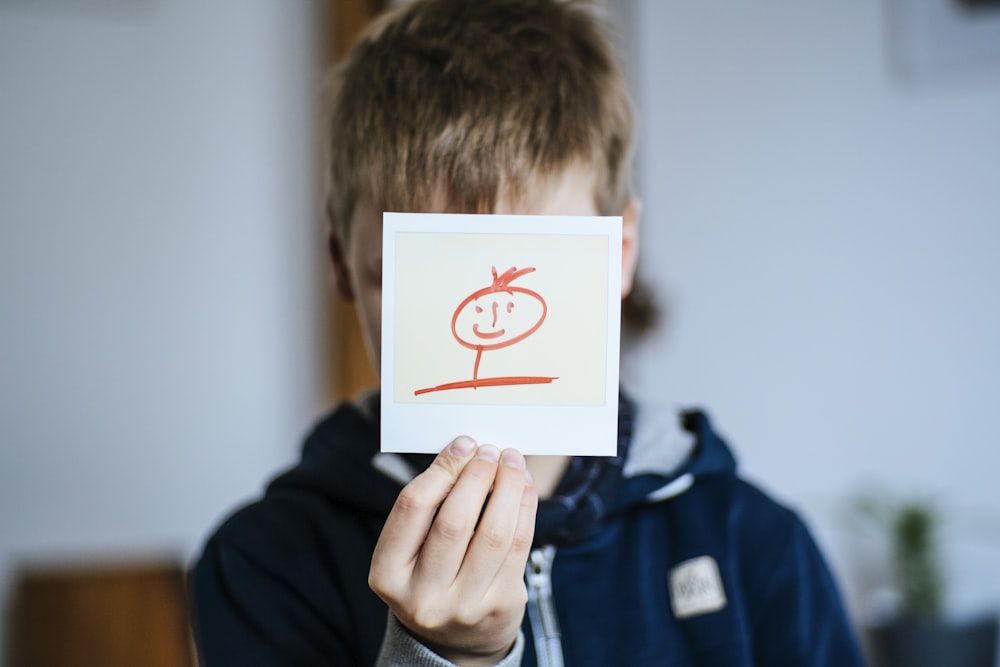 Junge hält weiße Karte mit Zeichnung