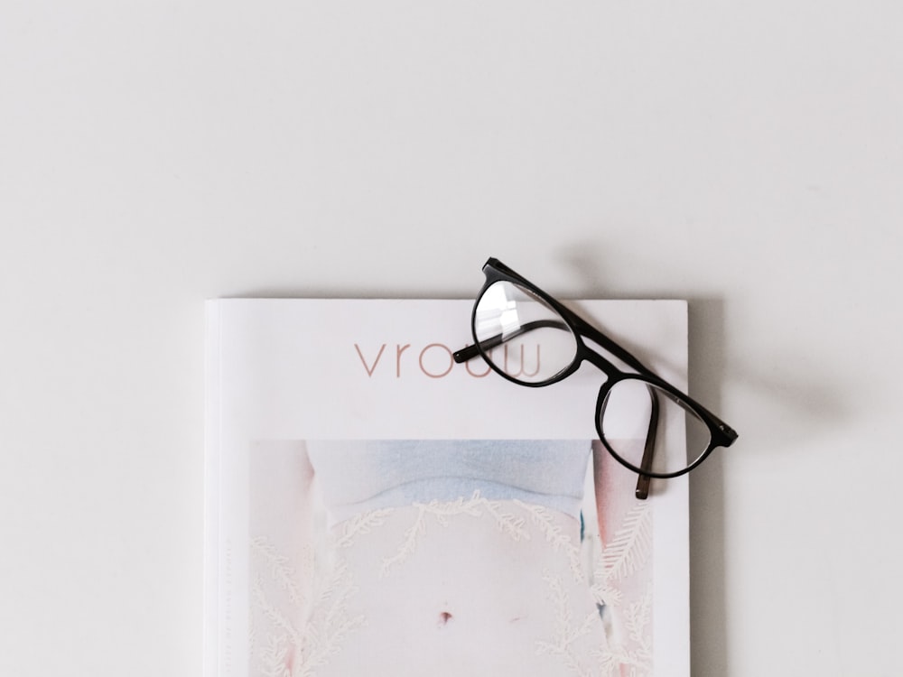black framed eyeglasses on white book