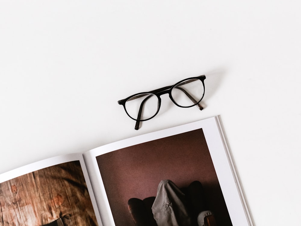 eyeglasses on top of photo album on white surface