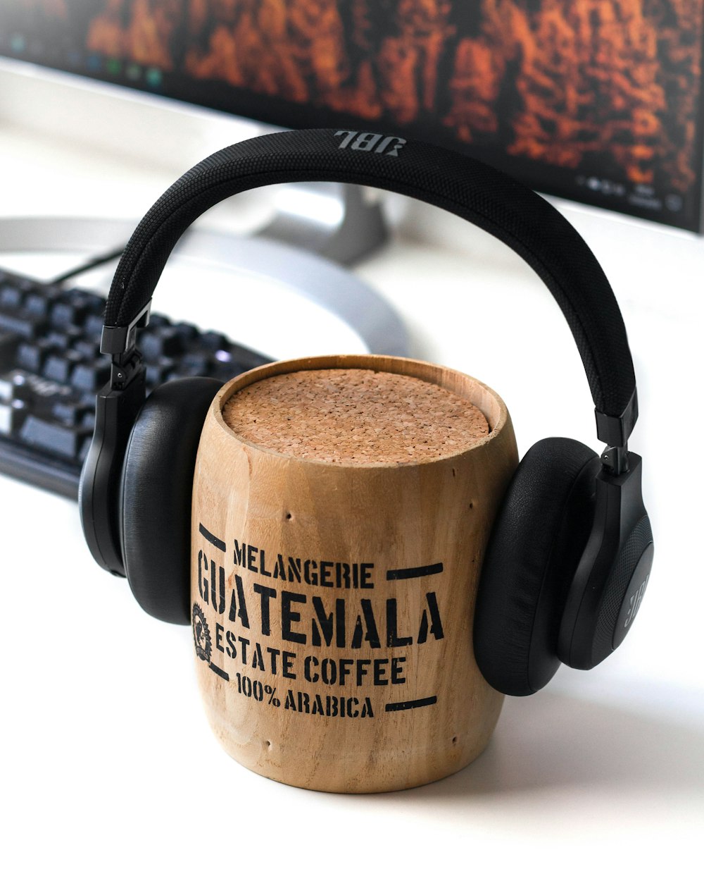 taza de madera marrón de Guatemala y auriculares JBL negros en ella